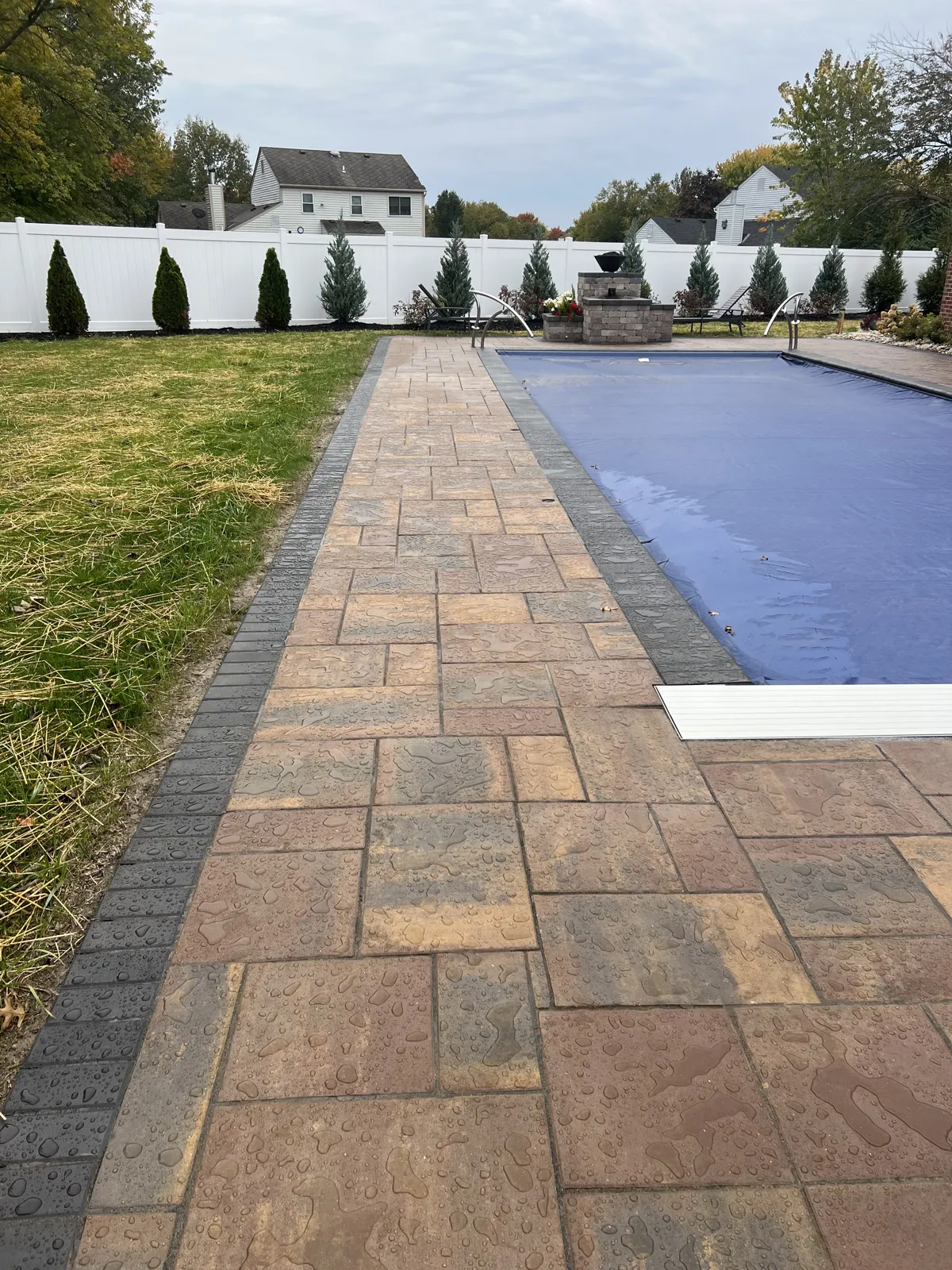 Long paver walkway running beside the pool with charcoal border