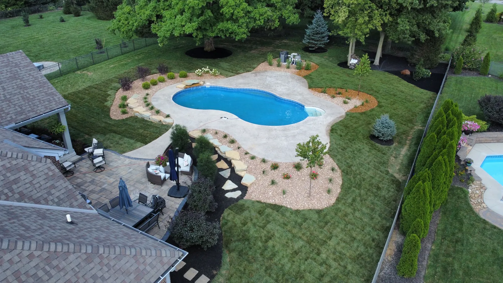 Drone view of a freeform pool, patio and landscape beds