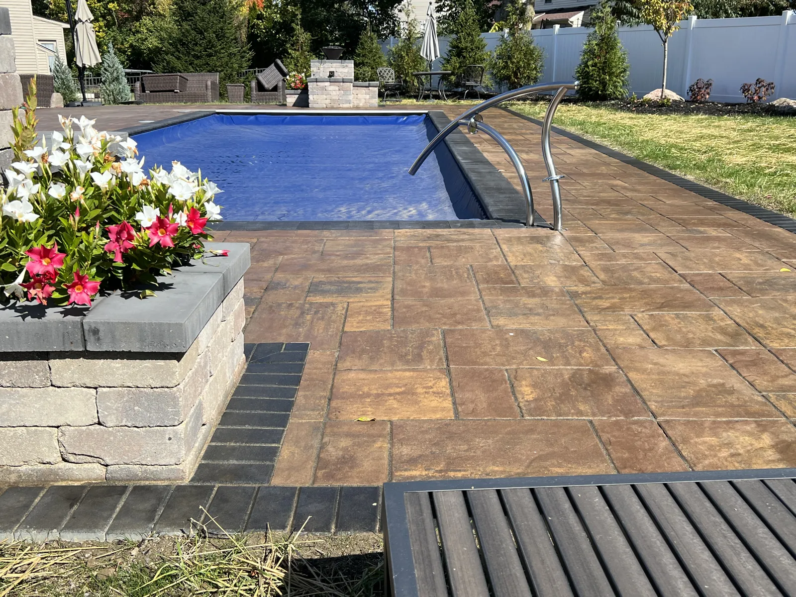 Paver pool deck with stone planter of flowering mandevilla