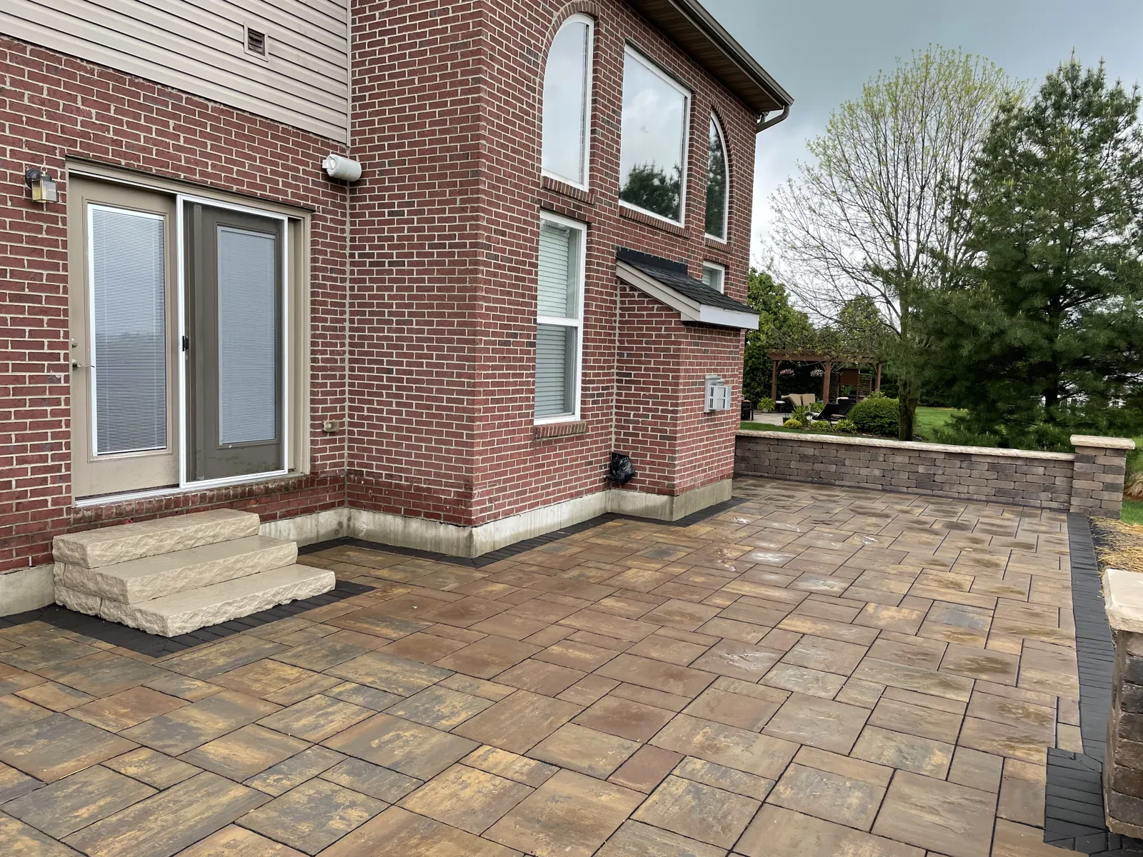 Large paver patio with stone steps at the back door
