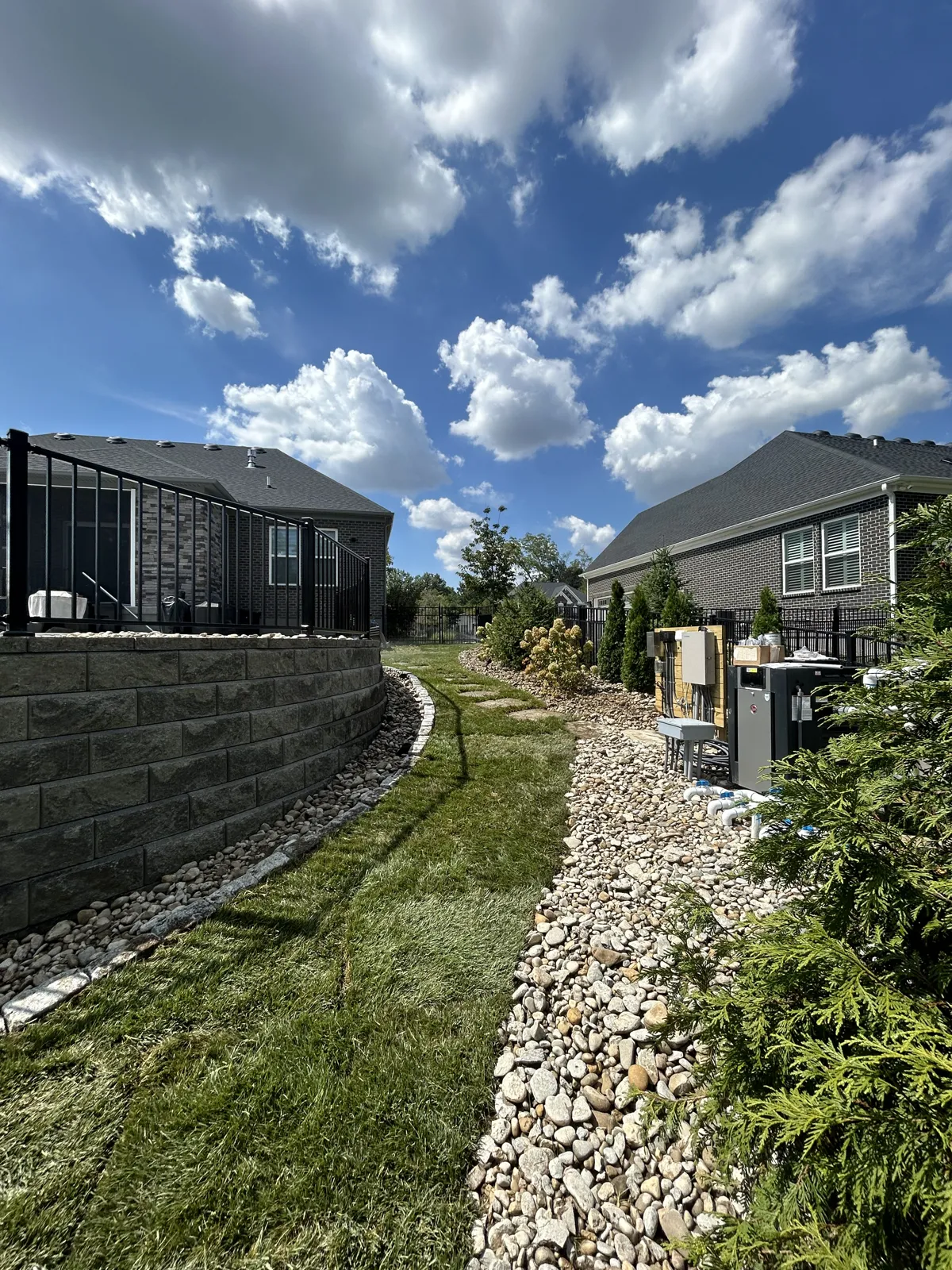 Block retaining wall with a river rock drainage swale built by TJs Landscaping