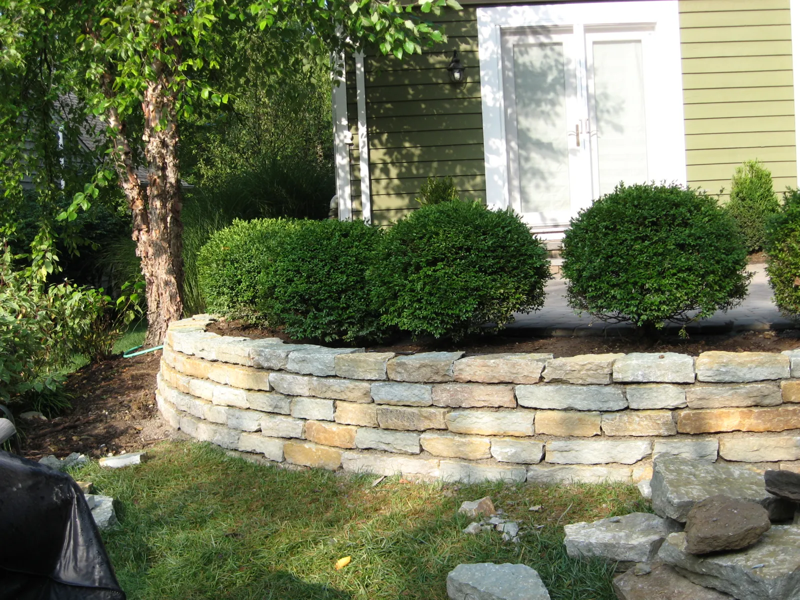 Stacked stone retaining wall topped with clipped boxwoods