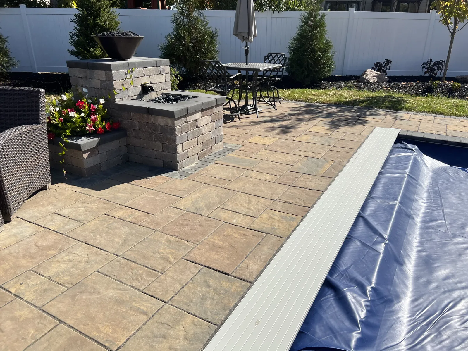 Stone columns with fire bowls beside the paver pool deck
