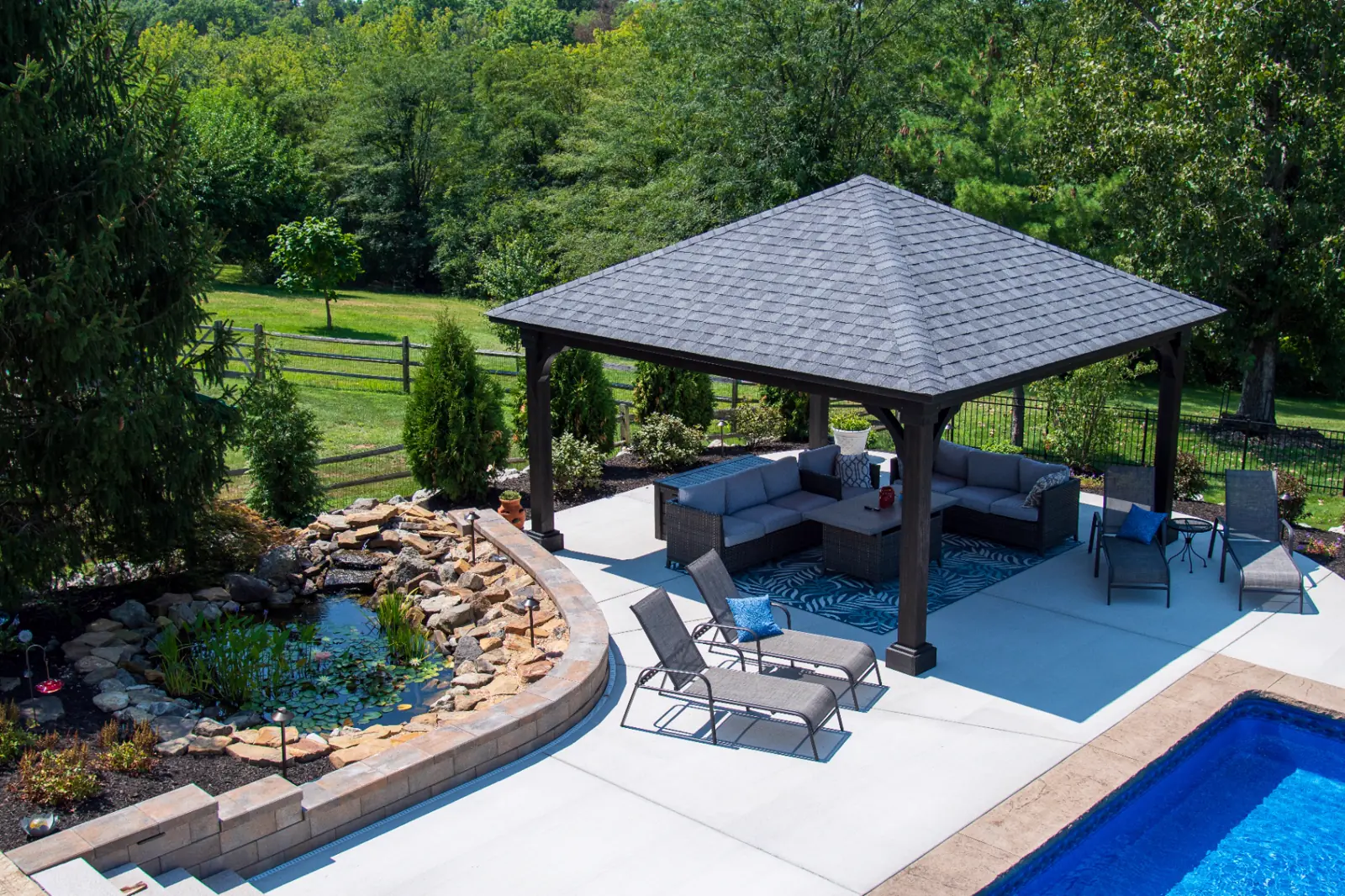 Timber outdoor pavilion overlooking a natural stone waterfall pond and landscaped pool retreat