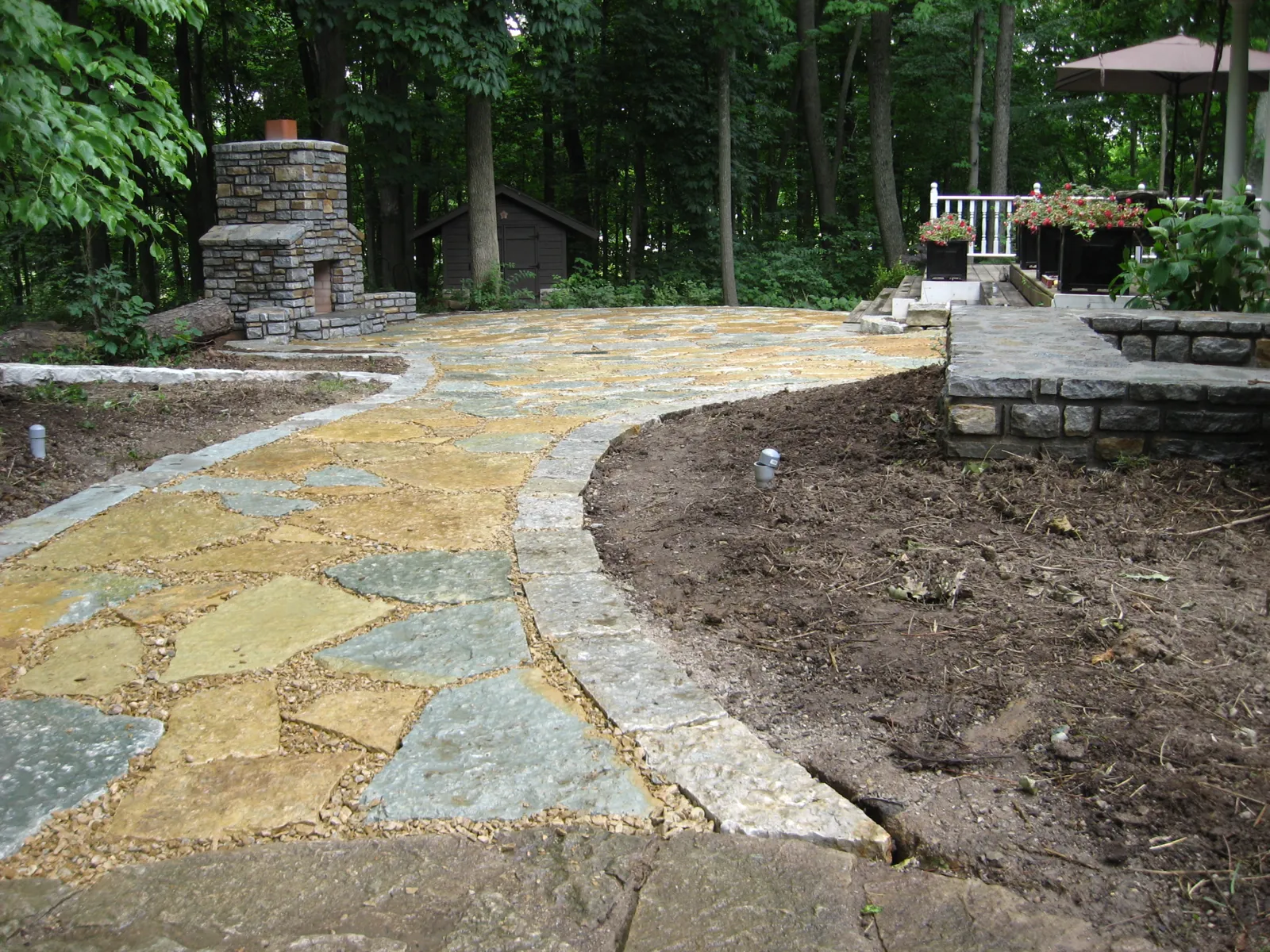 Curved flagstone walkway leading to a stone outdoor fireplace