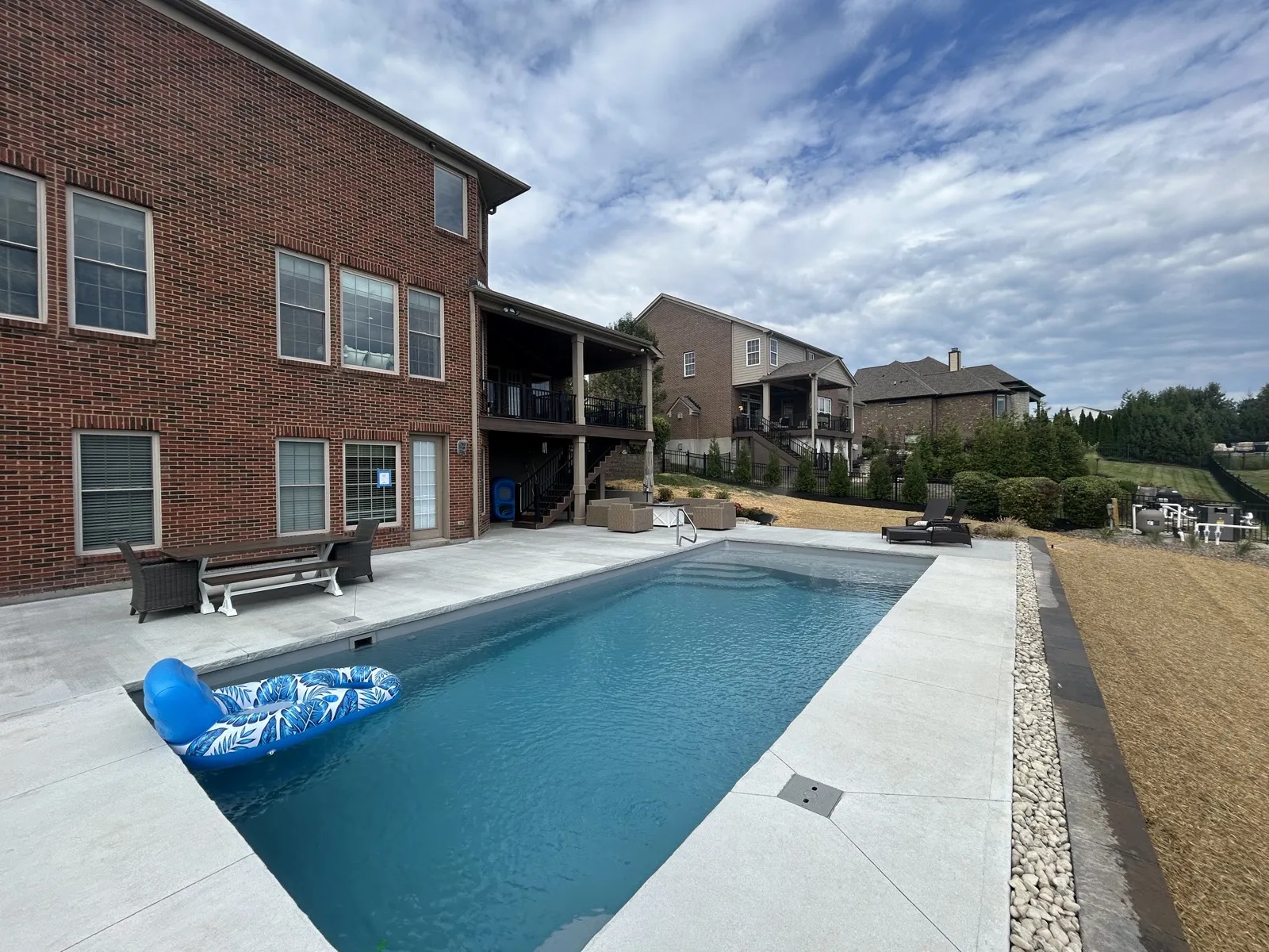 Concrete pool deck with river rock drainage border