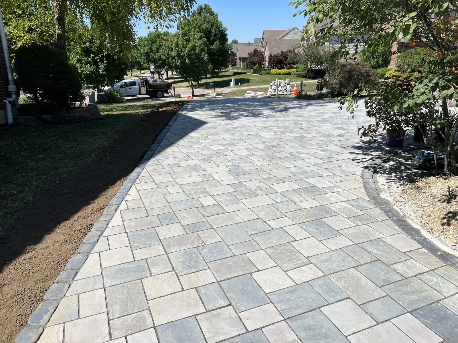Wide paver driveway with charcoal soldier course border and fresh plantings