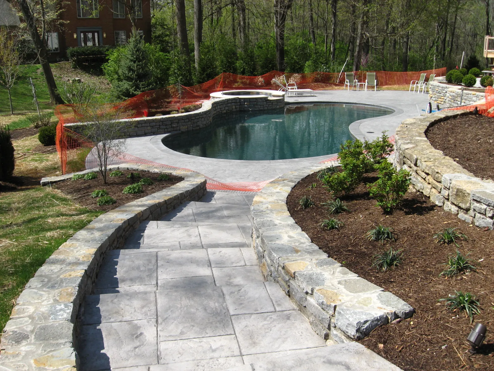 Stamped walkway between limestone walls leading to the pool