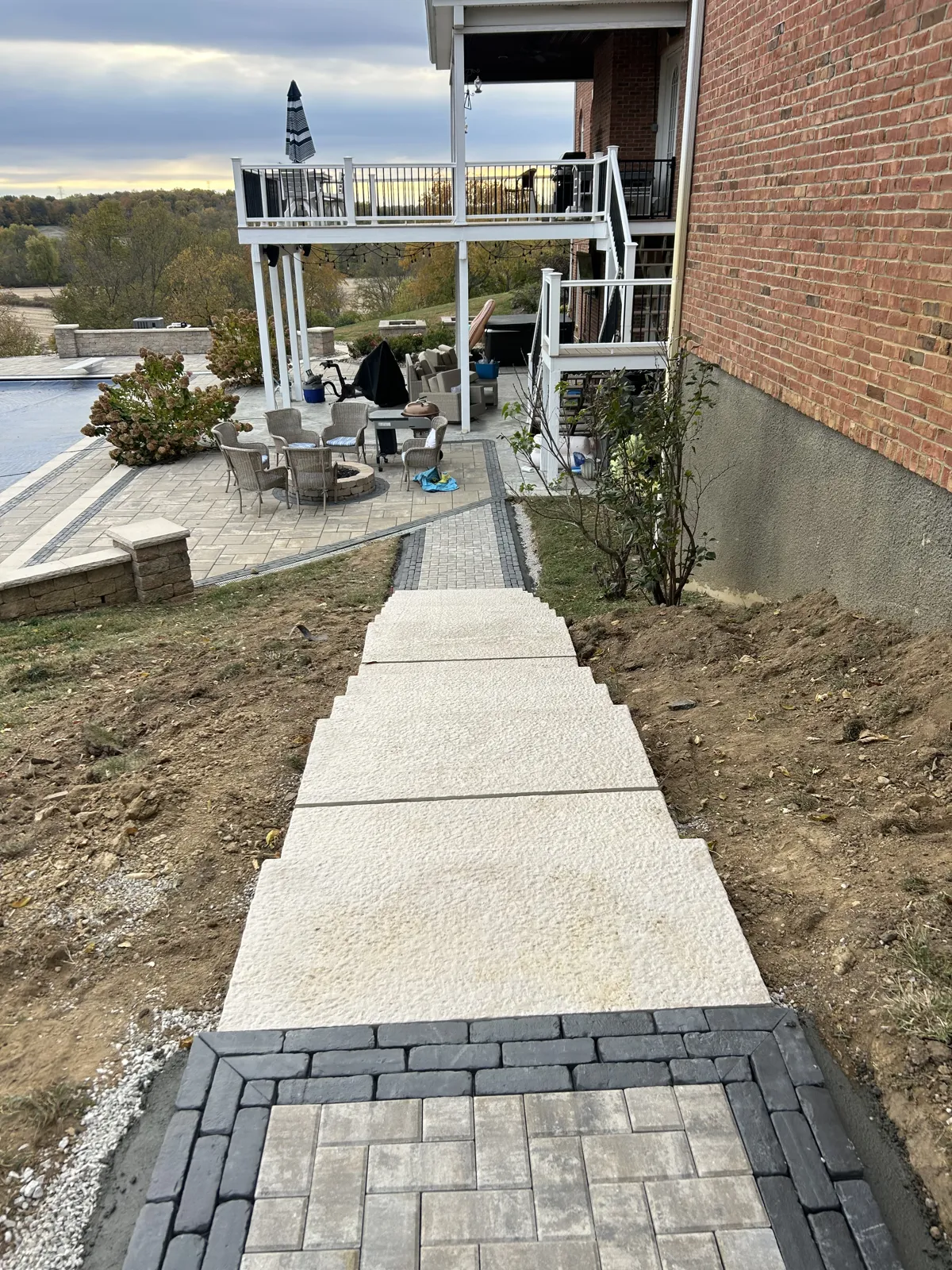 Concrete stair walk with paver landing beside a pool