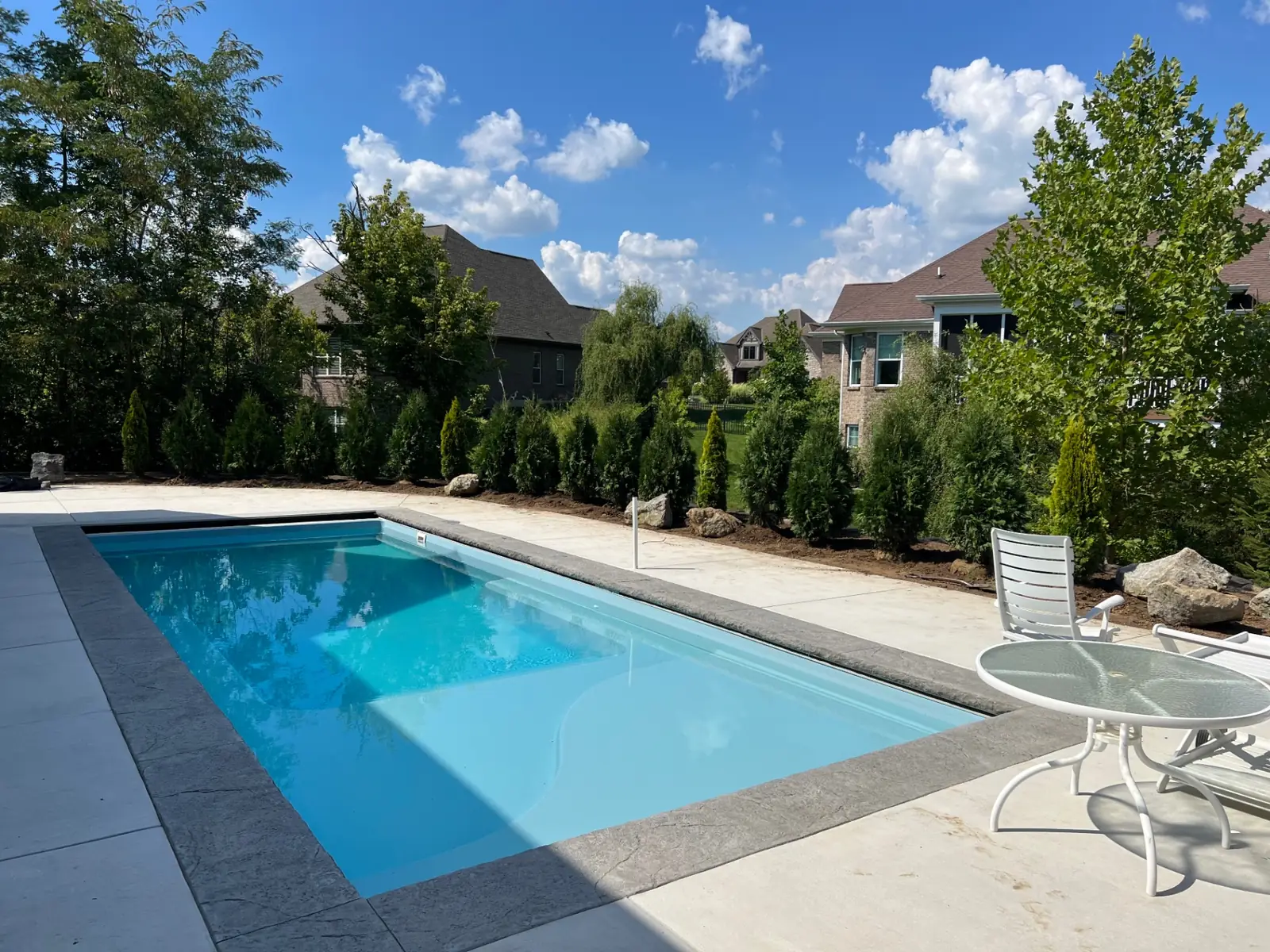 Finished rectangular pool and coping under a clear blue sky