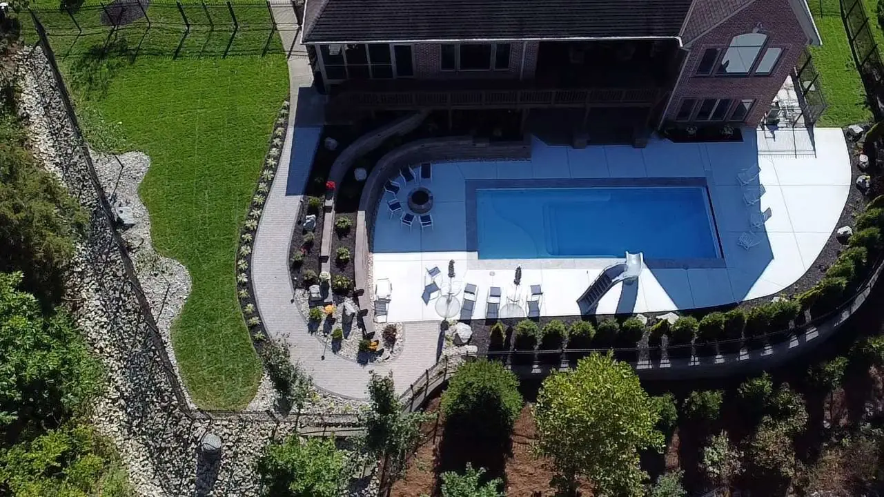 Aerial view of a multi-level backyard pool with slide, fire pit and outdoor living areas