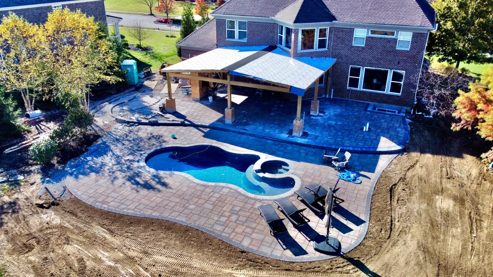 Aerial view of a covered pavilion and expansive paver pool deck