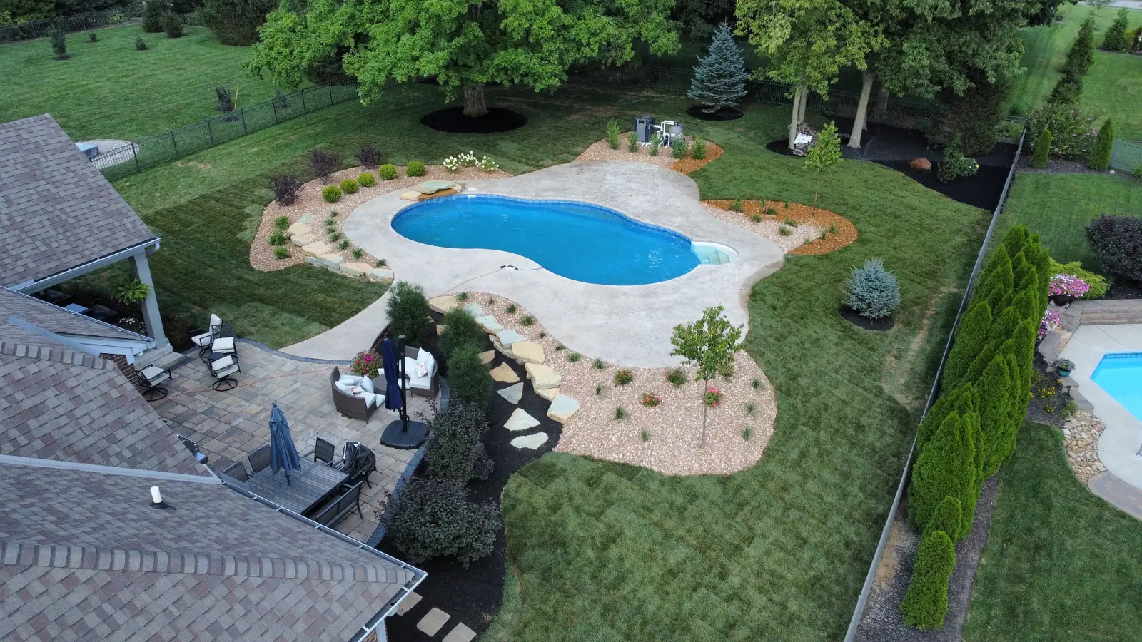 Aerial view of a freeform pool, patios and landscaped grounds completed by TJ's Landscaping